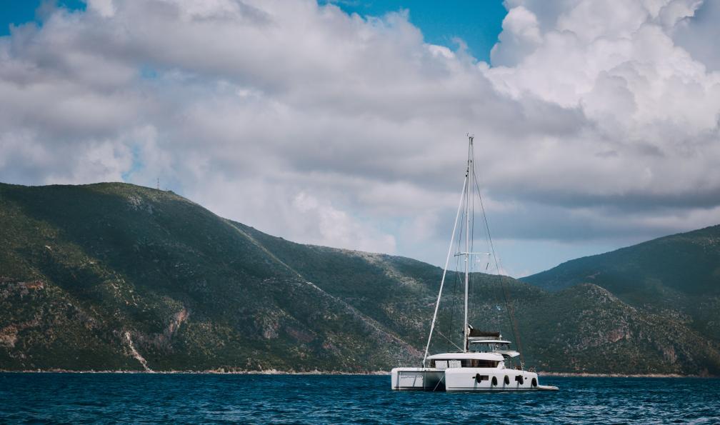 Tichonow - Igor - Adobestock - Un catamaran, voilier, en pleine mer près de Fiskardo, avec de gros nuages se déplaçant au-dessus des formes montagneuses de lîle dIthaque. Île de Céphalonie, Grèce. - Voile et rando en mer Ionienne  - 3