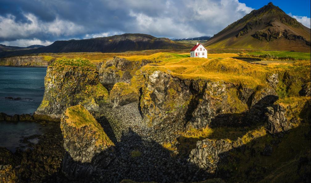 fotoVoyager -  Istock -  Maison blanche sur la côte de l'océan spectaculaire sur rocky mountain Snaefellsnes, Islande. - Le tour du pays de feu - 1