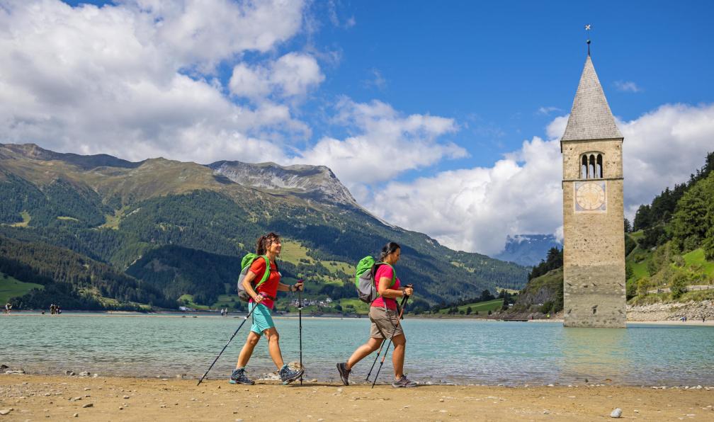 Eurofun - Des randonneurs marchent devant l'ancienne église de Graun désormais submergée dans le lac Resia en Italie. - De la Bavière au Sud Tyrol - 6