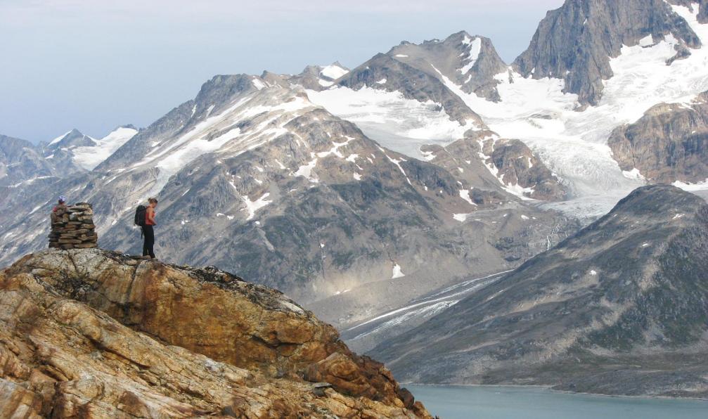 Randonneur près d'un cairn, au-dessus d'un fjord entouré de montagnes et de glaciers, Groenland Est. - Trek en terre Inuit - 5