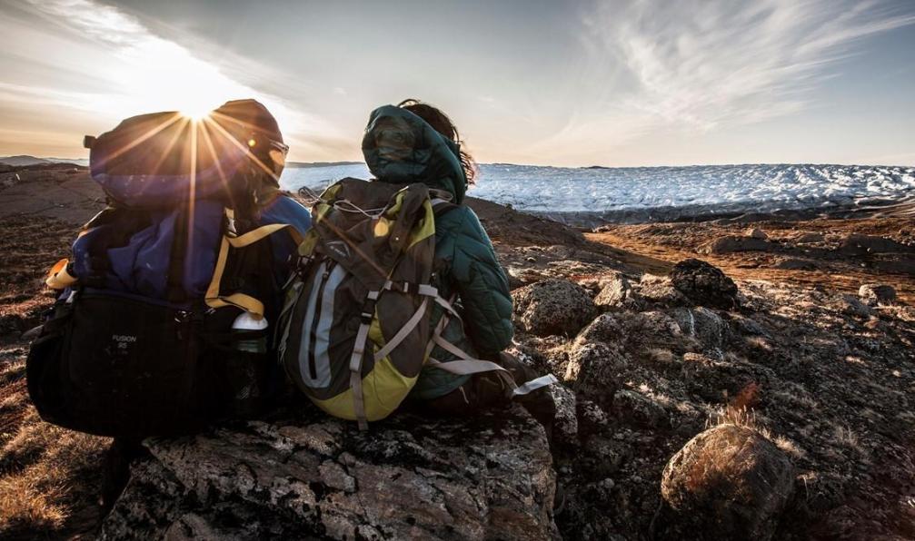 Arctic Hiking -  Randonneur faisant une pause au bord de la la côte devant une mer d'iceberg;groenland - Sermilik, trek au royaume des icebergs - 2