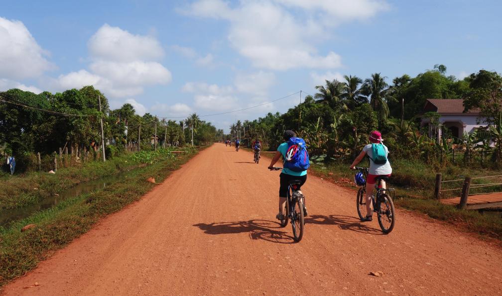 Claire Spaïni -  Groupe de personnes à vélo sur une route en terre, Cambodge.  - Au coeur du Cambodge - 5