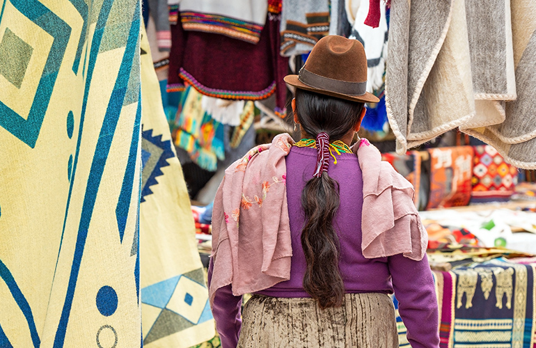 Equatorienne sur un marché entourée de tissu traditionnels, Équateur