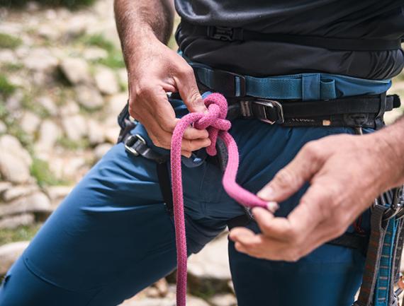 Cadrage sur un homme réalisant un noeud pour escalader une paroi