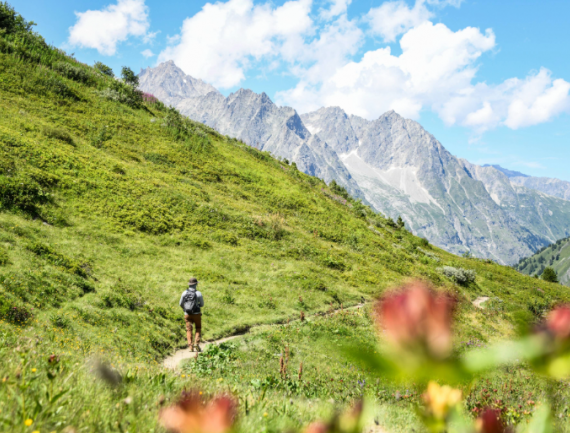 Randonneur sur le sentier du tour du Mont-Blanc avec au loin de la Glacier de l'A Neuve, Alpes, France