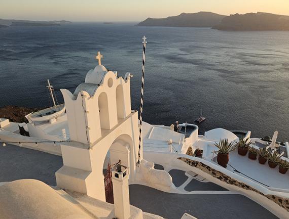 Chapelle à Oia avec vue sur la mer et les autres îles au coucher du soleil, Santorin, Cyclades, Grèce.