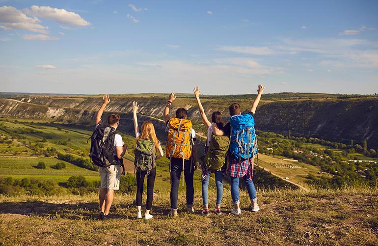 Groupe de marcheurs de dos face à un paysage verdoyant.
