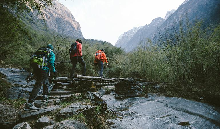 Groupe de marcheurs traversant un pont au dessus d'une rivière.